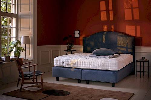 Stylishly decorated bedroom with blue Vispring boxspring