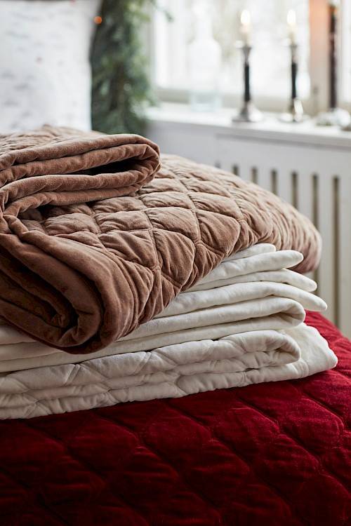 Stacked bedspreads in various colors